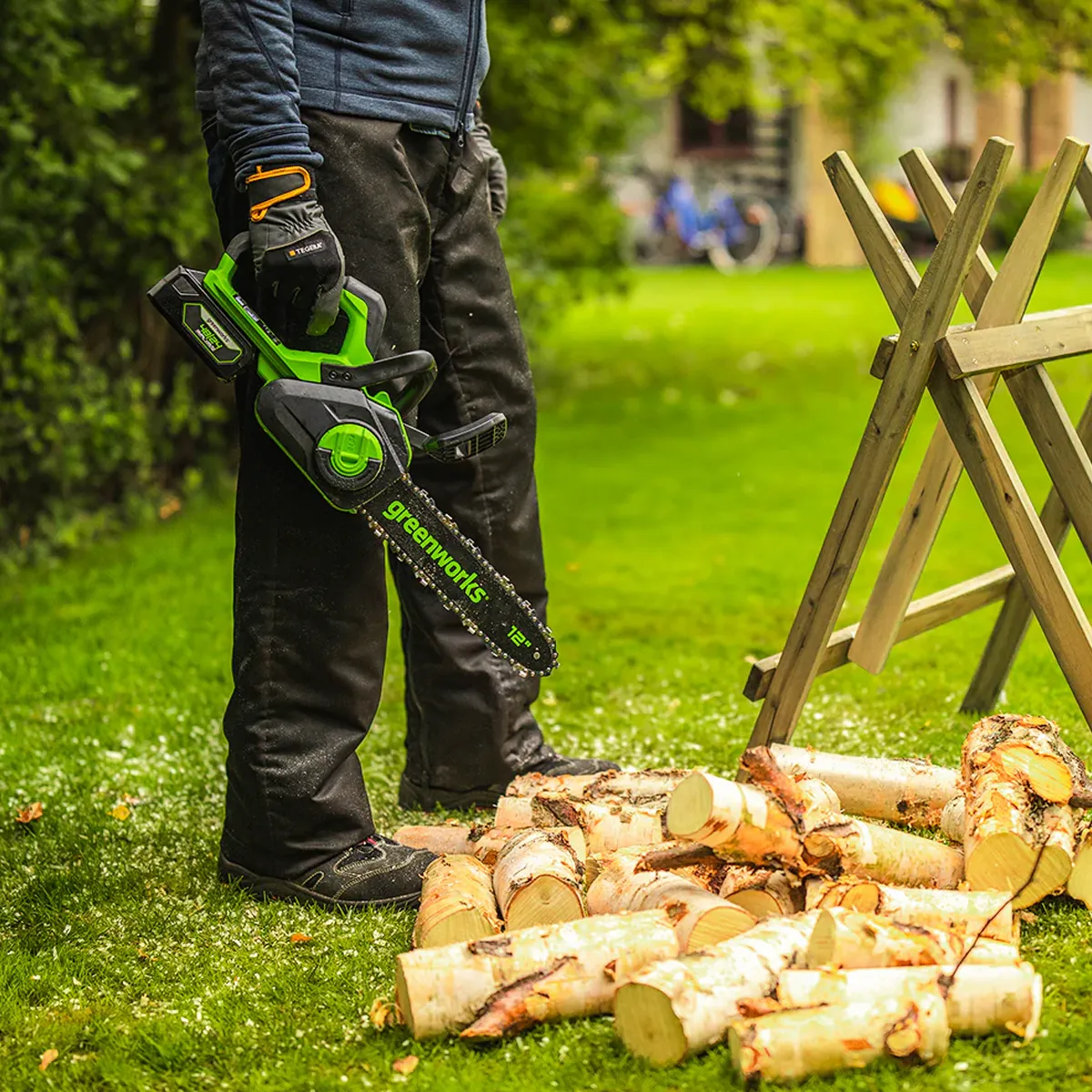 Greenworks 24V keðjusög 30 cm – keðjusög borin við stafla af eldiviði